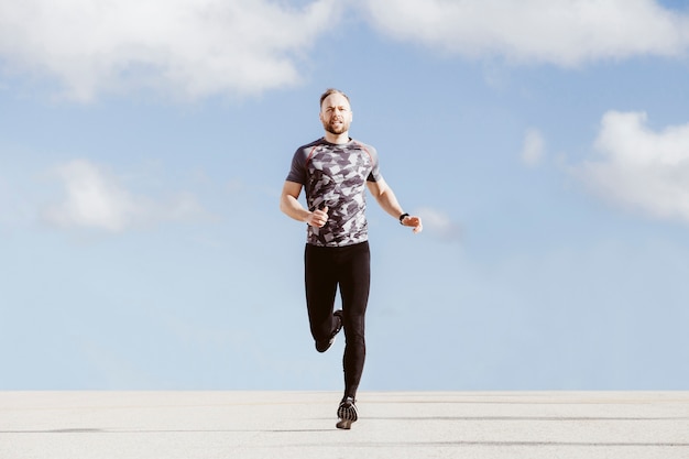 Runner running on boardwalk against cloudy sky