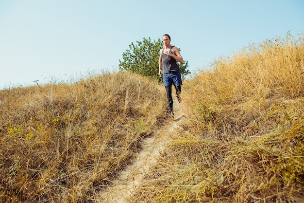 Running sport. Man runner sprinting outdoor in scenic nature. Fit muscular male athlete training trail running for marathon run.