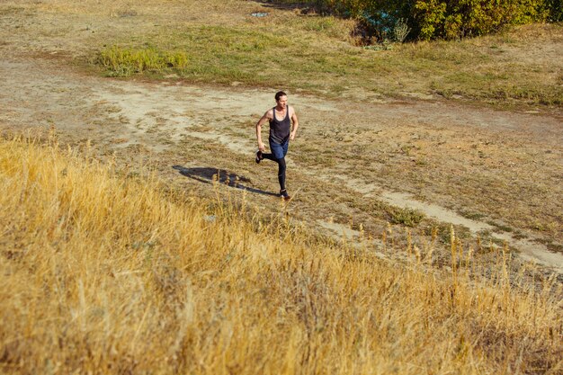 スポーツを実行します。風光明媚な自然の中で屋外全力疾走の男性ランナー。マラソンの実行のために実行している筋肉の男性アスリートトレーニングトレイルに適合します。