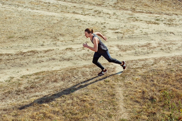 Running sport. Man runner sprinting outdoor in scenic nature. Fit muscular male athlete training trail running for marathon run.