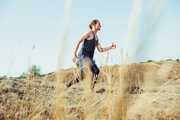 Running sport. Man runner sprinting outdoor in scenic nature. Fit muscular male athlete training trail running for marathon run.