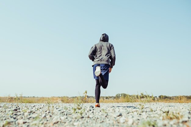 Running sport. Man runner sprinting outdoor in scenic nature. Fit muscular male athlete training trail running for marathon run.