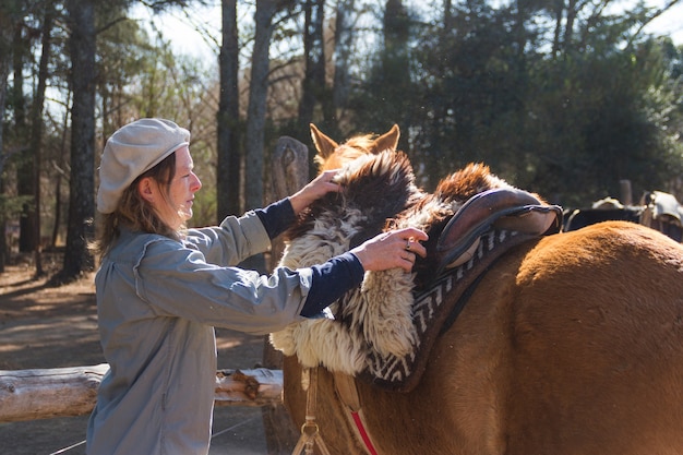 Donna rurale che sella il suo cavallo nel campo