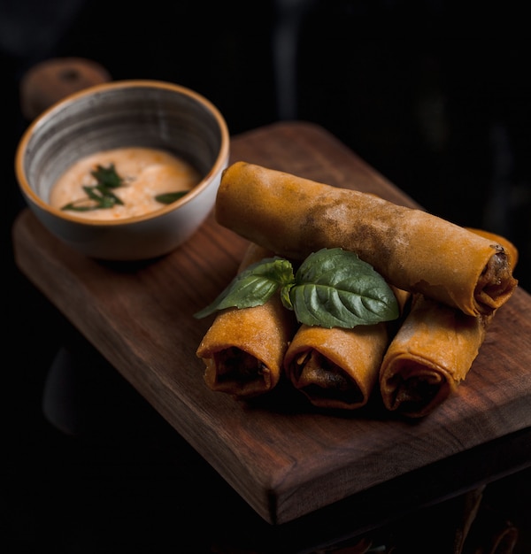 Russian blinchik with fresh basilic leaves and sauce.