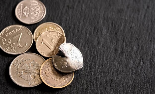 Russian coins on a black stone background deformed and broken money The idea of the collapse of the ruble and the economy sanctions against Russian aggression layout with copy space