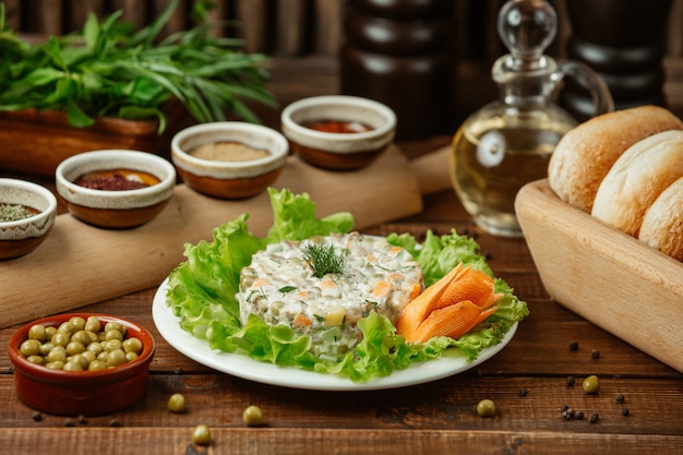 Russian salad stolichni served on green salad leaves and decorative carrot with green beans