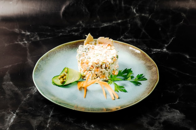 Russian stolichni salad in a rustic ceramic plate with vegetables and herbs.