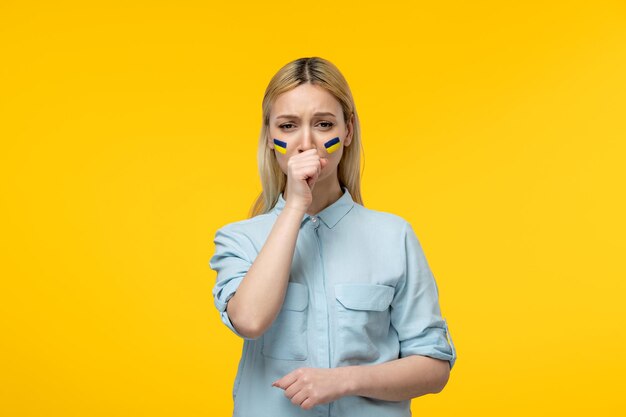 Russian ukrainian conflict cute girl yellow background with ukrainian flag on cheeks crying