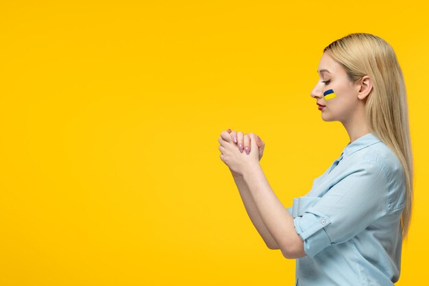 Russian ukrainian conflict cute girl yellow background with ukrainian flag on cheeks holding hands