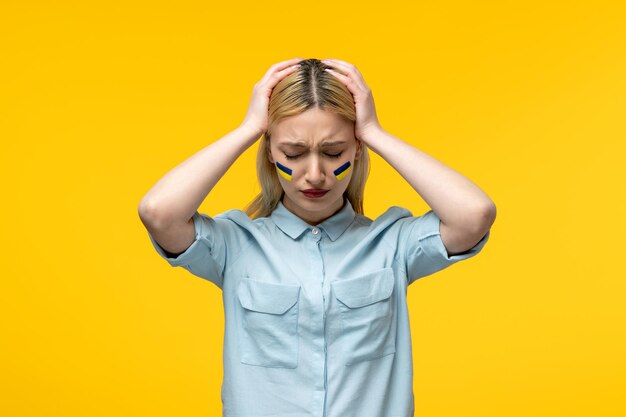 Russian ukrainian conflict cute girl yellow background with ukrainian flag on cheeks scared