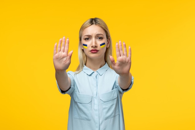 Russian ukrainian conflict cute girl yellow background with ukrainian flag on cheeks stopping war