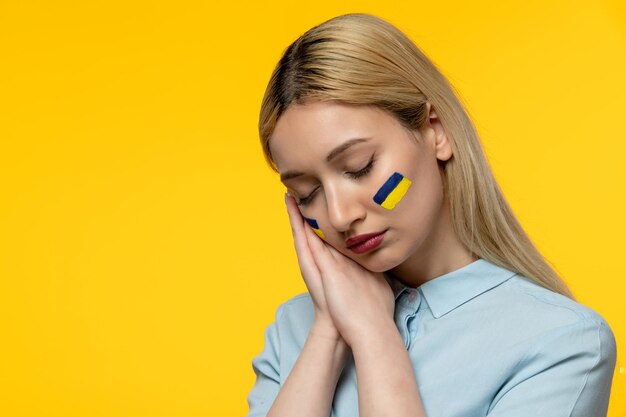 Russian ukrainian conflict young cute girl with ukrainian flag on cheeks peaceful closing eyes