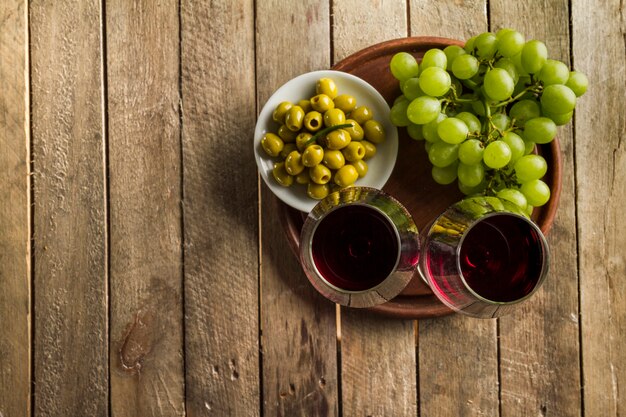 Rustic background with grapes, wine glasses and olives