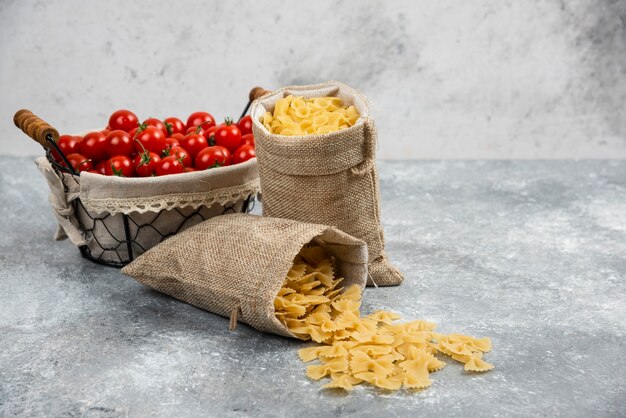 Rustic baskets of pasta with cherry tomatoes on a marble table.