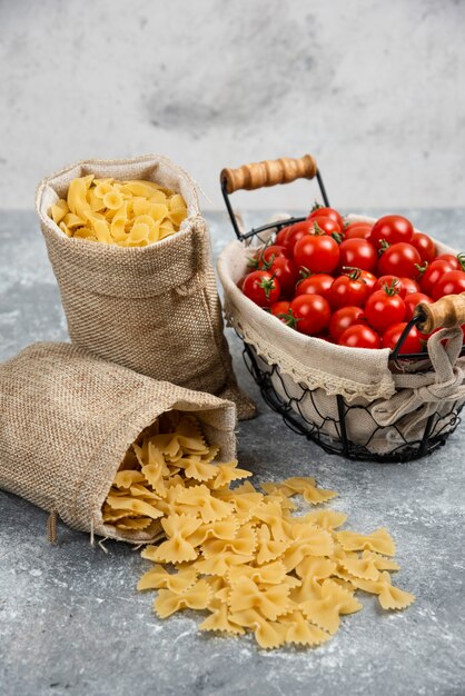 Rustic baskets of pasta with cherry tomatoes on a marble table.