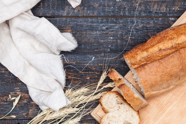 Rustic bread on wood table with wheat and cloth