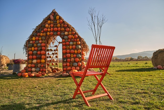 Rustic chair and artificial real size pumpkin house in green lawn in november low angle view of