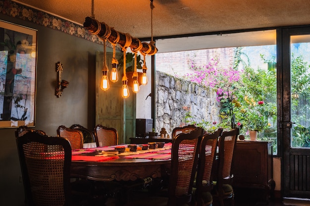 Rustic chandelier made of bulbs and ropes over a dining table in a vintage kitchen