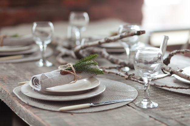 Rustic Christmas served wooden table with vintage silverware, candles and fir twigs.