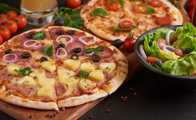 さまざまな種類のイタリアンピザを備えた素朴なダークストーンのテーブル、上面図。ファーストフードランチ、お祝い