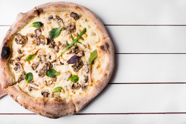 Rustic round mushroom pizza on white wooden table