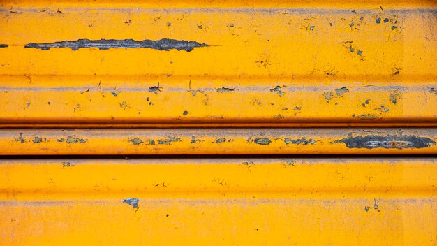 Rusty metallic wall with yellow paint