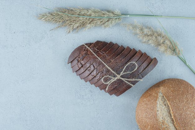 Rye bread slices and roll on stone surface with wheat