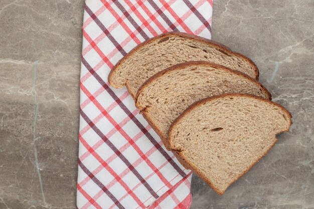 Rye bread slices and tablecloth on marble surface. High quality photo