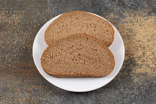 Ломтики ржаного хлеба на белой тарелке.