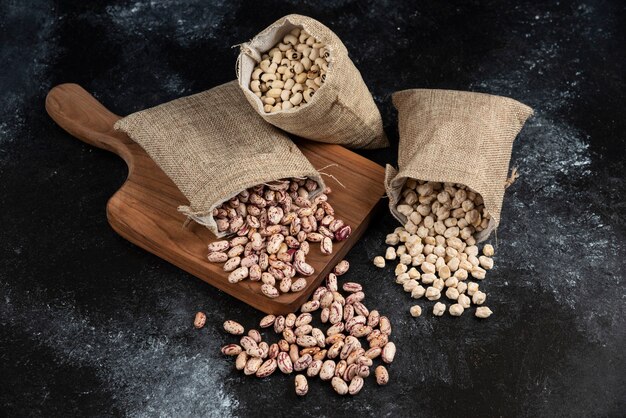 Sackcloth of dried raw beans placed on dark surface. .