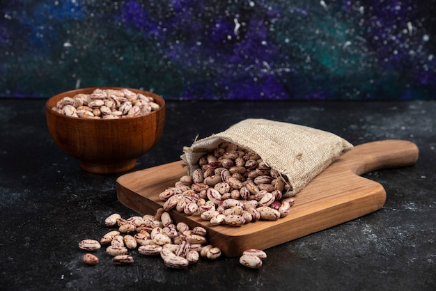 Free photo sackcloth of dried raw beans placed on wooden board.