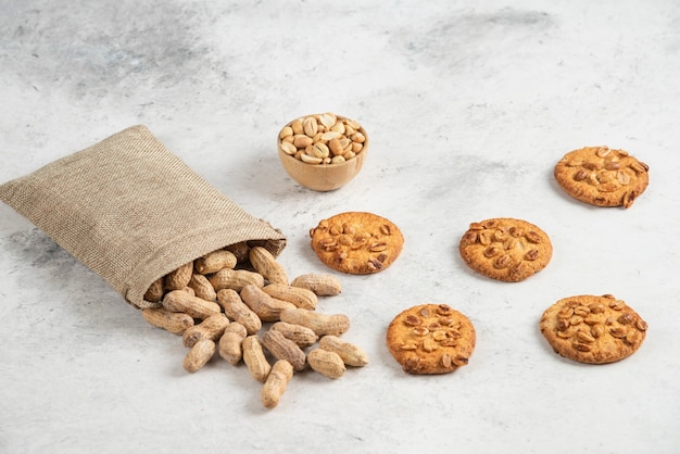 Sacco di arachidi organiche e deliziosi biscotti sul tavolo di marmo.