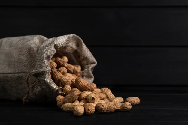 Sackcloth of organic peanuts for making butter placed on black background. High quality photo