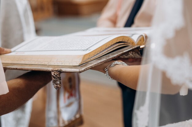 教会の秘跡の結婚式の儀式で花嫁の手に聖書の神聖な本