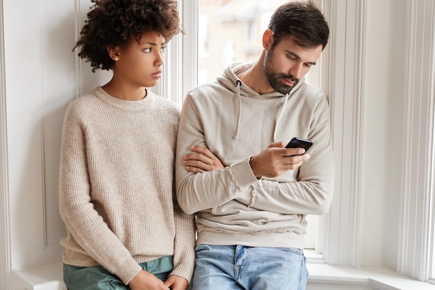 Sad African woman in oversized sweater feels displeased as being neglegted by boyfriend, needs lively communication