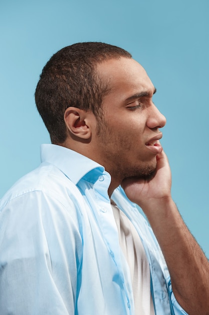 悲しいアフリカ系アメリカ人の男性が歯痛を抱えています。青い空間に対して