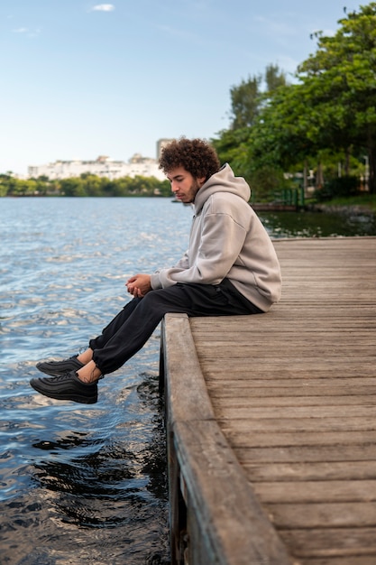 Бесплатное фото Грустный и задумчивый человек сидит у озера