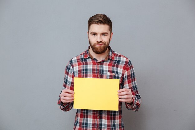 Sad angry bearded man holding blank paper