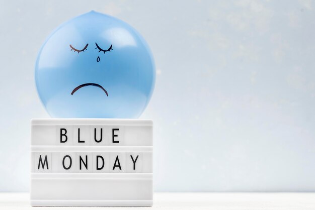 青い月曜日のライトボックスとコピースペースの悲しい風船