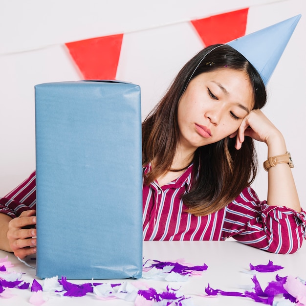 Free photo sad birthday girl with present box