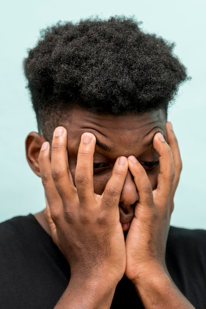 Sad black man with hands covering face