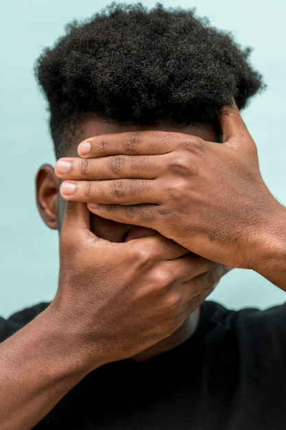 Sad black man with hands covering face