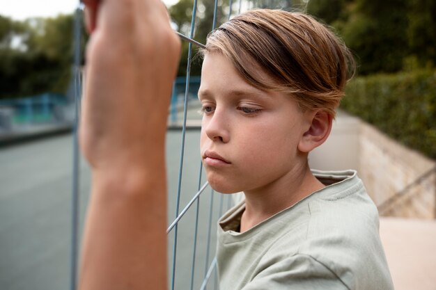 sad boy near fence side view