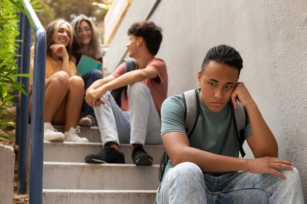 Free photo sad boy sitting on stairs low angle