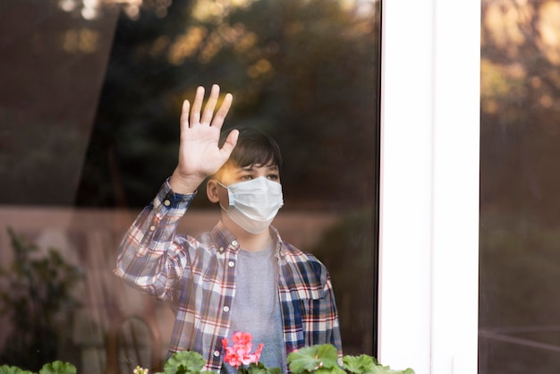 Sad boy with face mask on looking outdoors