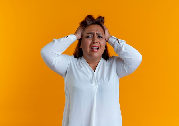 Sad casual caucasian middle-aged woman grabbed head isolated on yellow wall