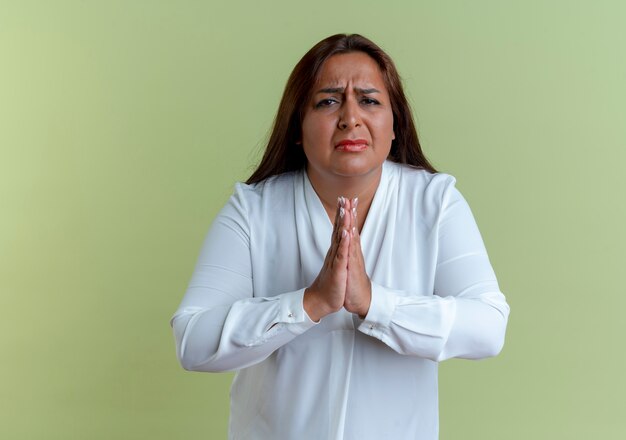 Foto gratuita donna di mezza età caucasica casuale triste che mostra pregare gesto isolato sulla parete verde oliva