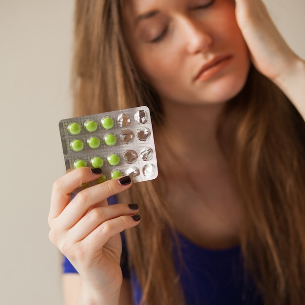 a woman with pills experiencing headache