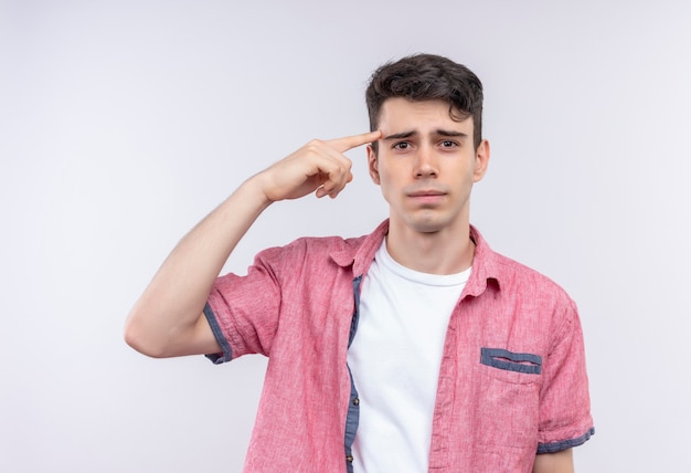 Sad caucasian young guy wearing pink shirt put his finger on forehead on isolated white background