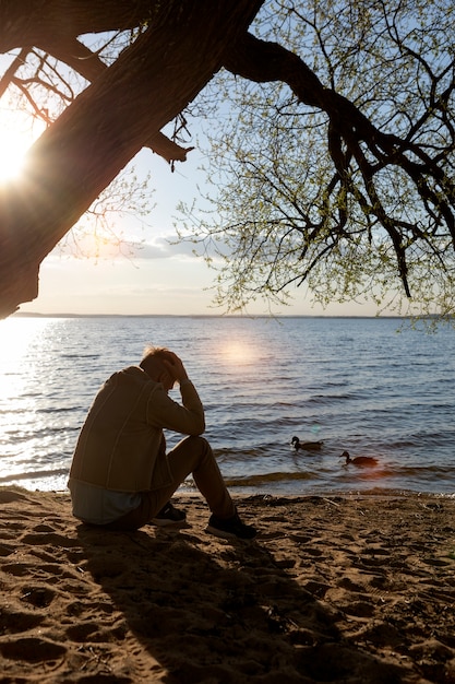 Foto gratuita persona triste e contemplativa vicino al lago